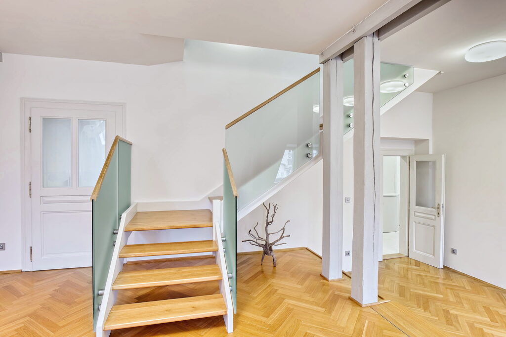 Světlá vstupní hala s moderním dřevěným schodištěm