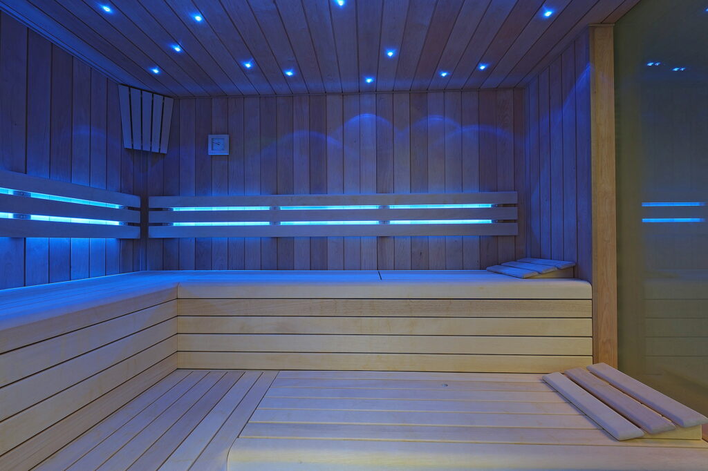 Moderní sauna s dřevěnými lavicemi a modrým ambientním osvětlením